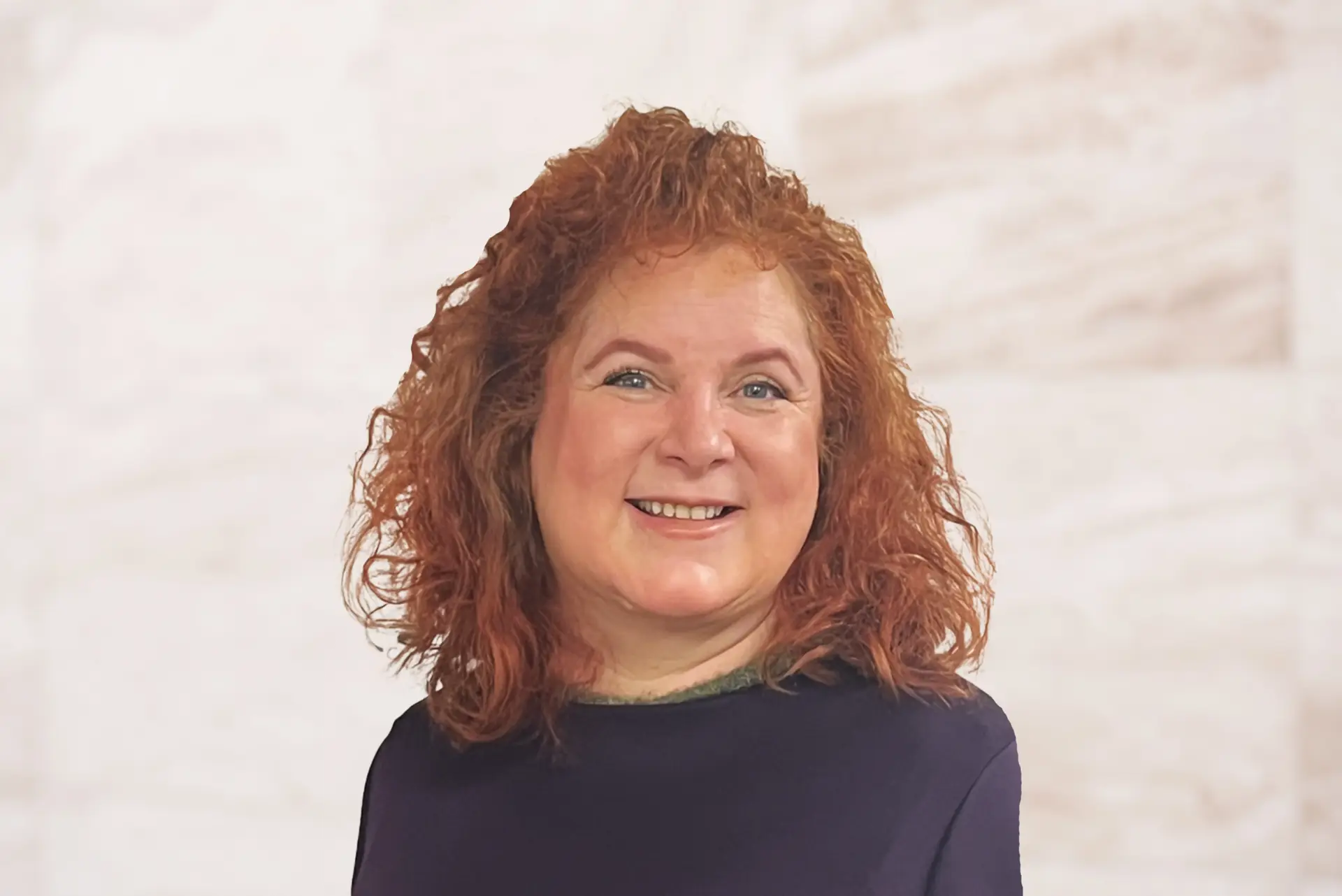 Jessica Lesser, attorney at the Law Office of Bryan Fagan, smiling confidently, with curly red hair, wearing a dark top, against a light background, representing her approachable and compassionate legal expertise.